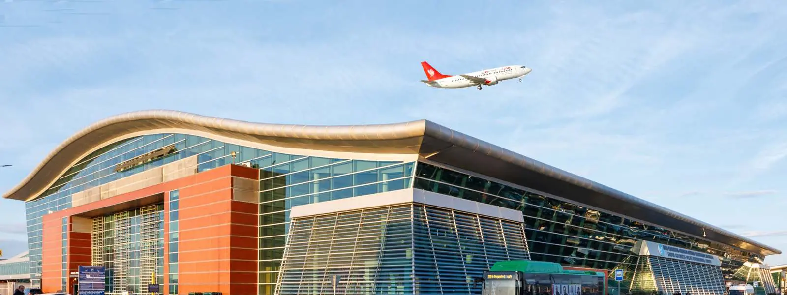 Aircraft flying over Tbilisi Airport, blue sky.
