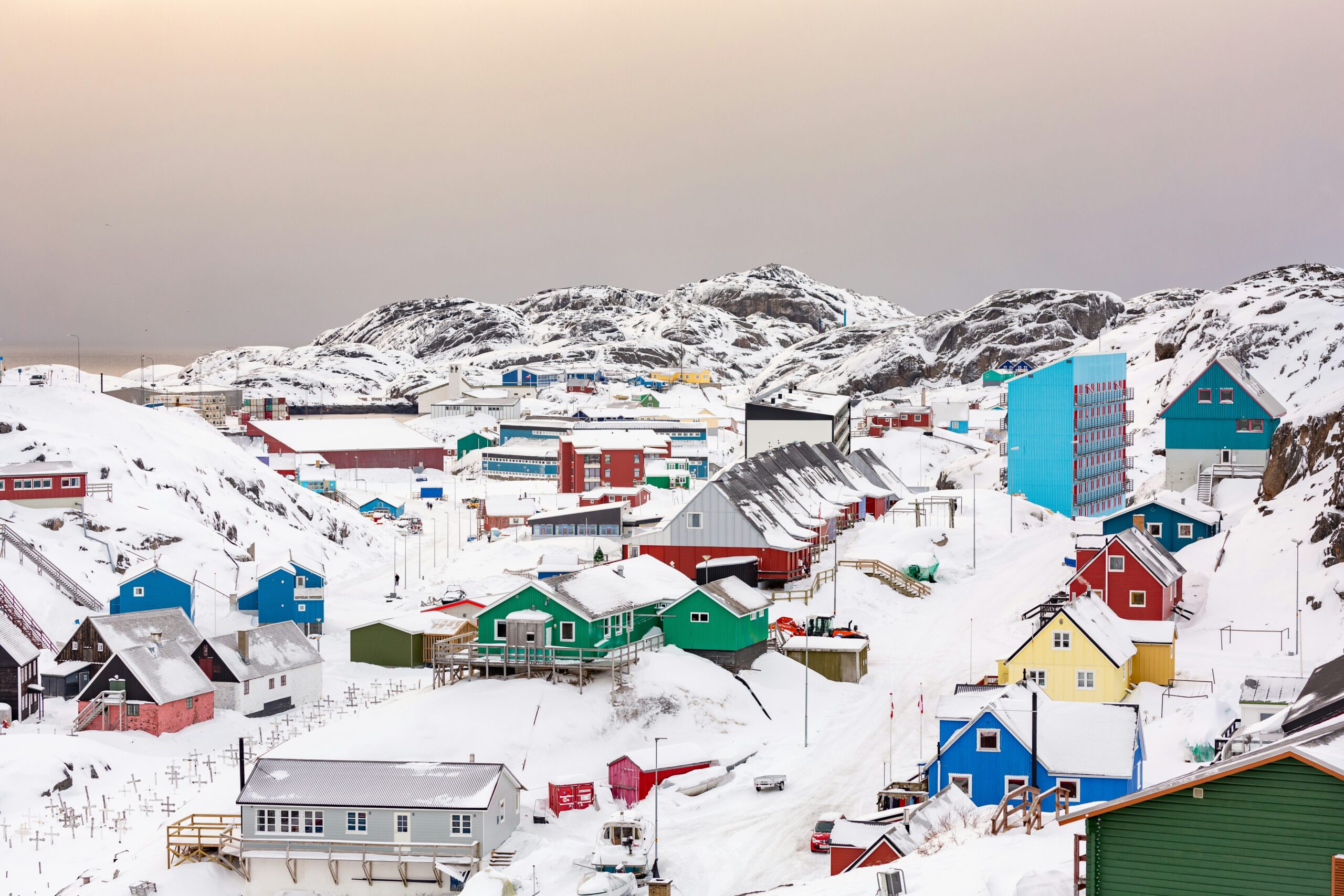 View over the town of Maniitsoq, Greenland - showing colorful buildings dotted around the snowy landscape.