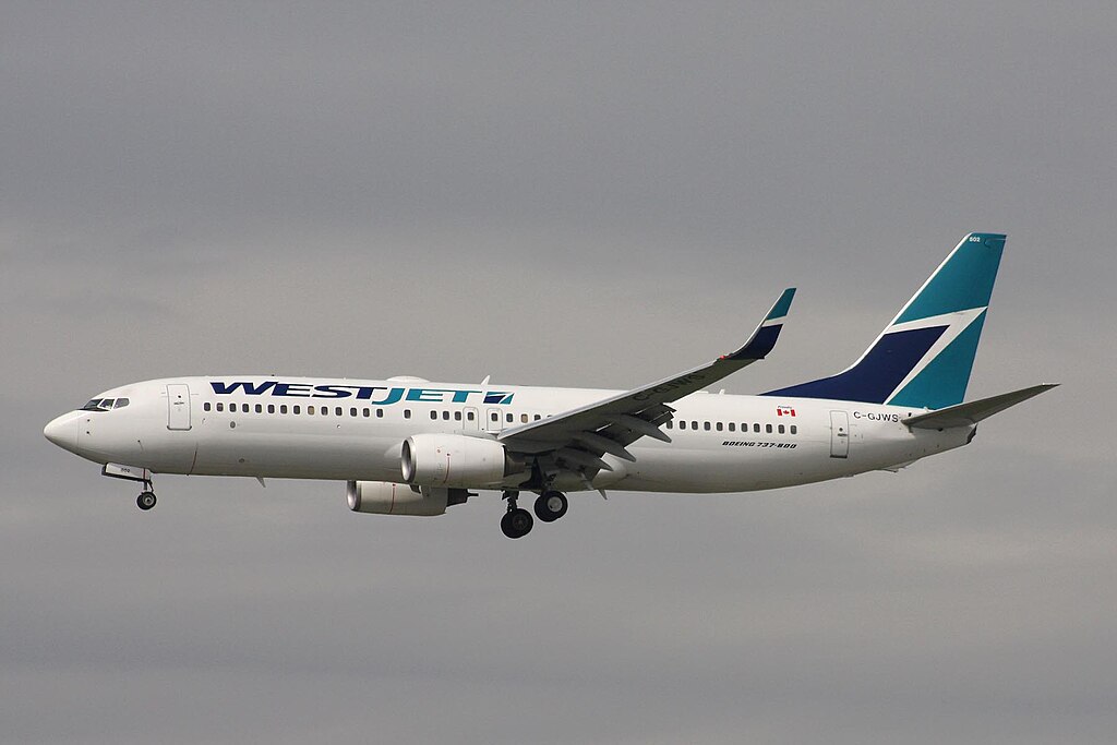 A WestJet aircraft flying in a grey sky