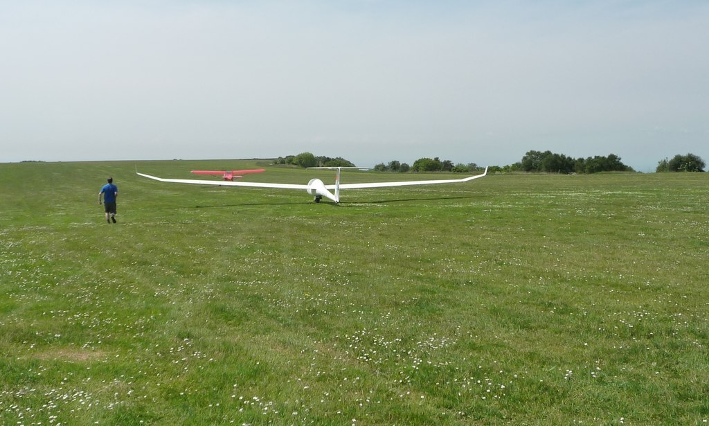 tow plane, green grass, clear skies, one figure of a person