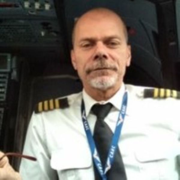 Pilot Brad Schlenker looking directly at the camera while wearing a pilot uniform inside an aircraft cockpit.