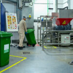 Worker rolling green bin with food