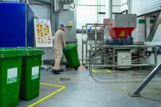 Worker rolling green bin with food