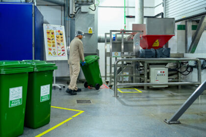 Worker rolling green bin with food