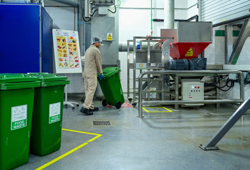 Worker rolling green bin with food