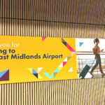 Arrival hall at the East Midlands Airport; welcoming poster on the wooden panel wall.
