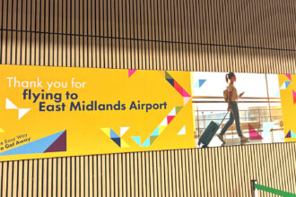 Arrival hall at the East Midlands Airport; welcoming poster on the wooden panel wall.