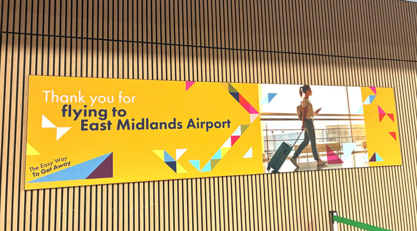 Arrival hall at the East Midlands Airport; welcoming poster on the wooden panel wall.