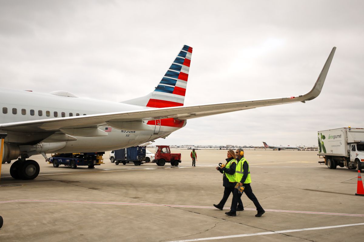 An American Airlines aircraft on the airport tarmac with ground crew.