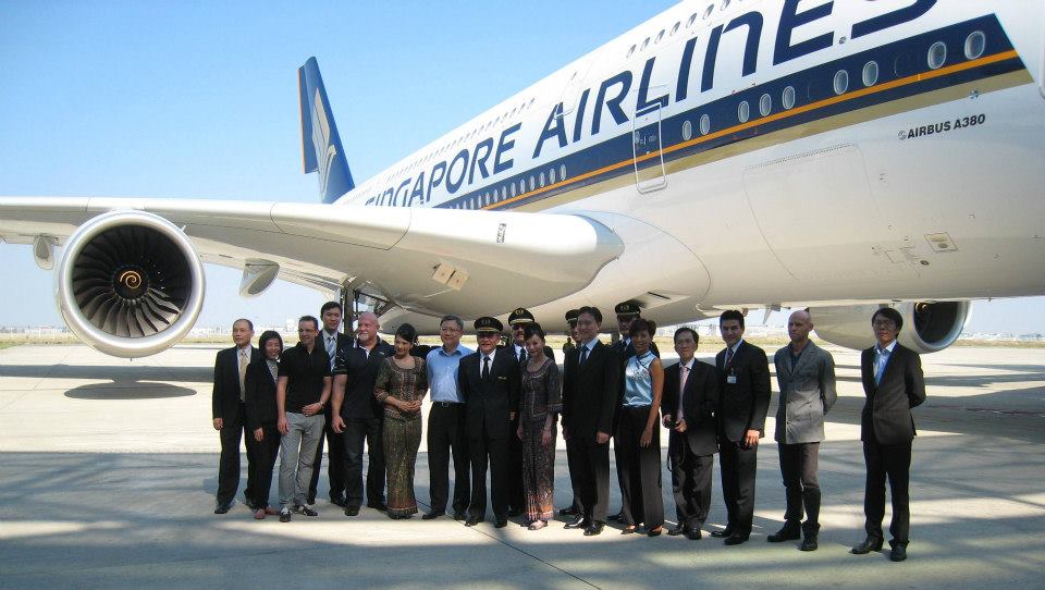 A group photo of Singapore Airlines staff stood on the tarmac in front of aircraft.