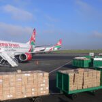 A Boeing 737 of Kenya Airways at the tarmac of the Jomo Kenyatta International Airport. Some parcels in the foreground.