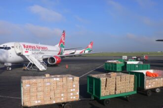 A Boeing 737 of Kenya Airways at the tarmac of the Jomo Kenyatta International Airport. Some parcels in the foreground.