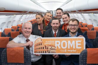 An easyJet crew aboard an aircraft celebrate the inaugural Glasgow-Rome flight with a sign reading "Glasgow Airport to Rome".