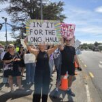 Air New Zealand cabin crew holding signs on a picket line during strike action.