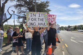 Air New Zealand cabin crew holding signs on a picket line during strike action.