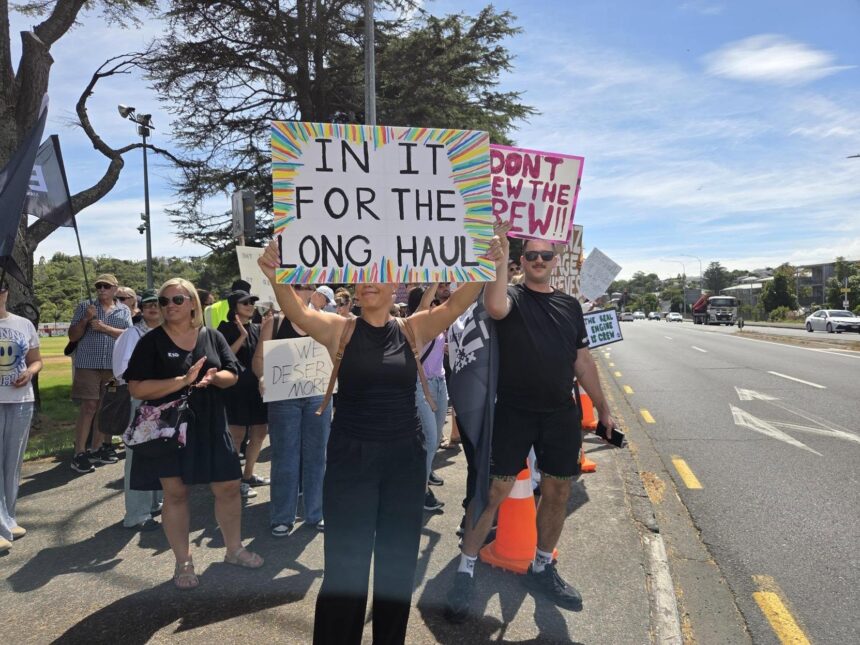Air New Zealand cabin crew holding signs on a picket line during strike action.