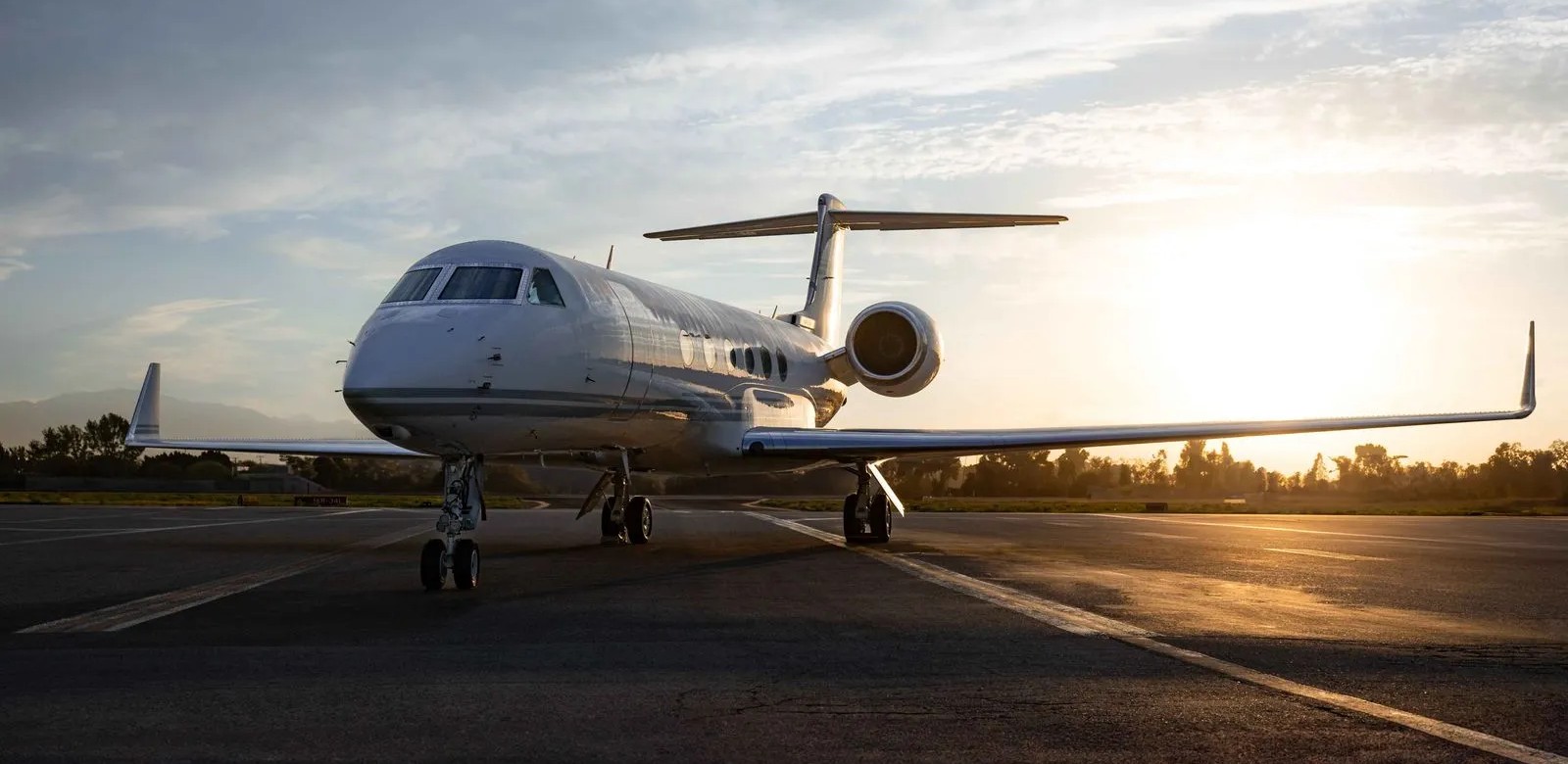 FlyHouse Gulfstream V aircraft on the tarmac, sun setting in the background.