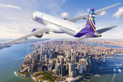 Avelo Airlines aircraft, flying over a city, blue sky.