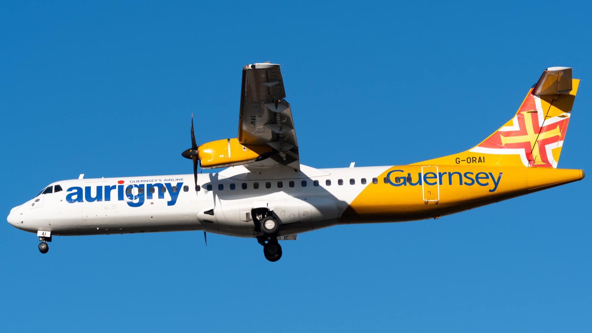 A Aurigny aircraft preparing to land in a blue clear sky