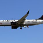 Air Canada Boeing 737-8 MAX flying, blue sky in background.