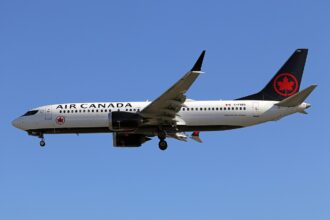 Air Canada Boeing 737-8 MAX flying, blue sky in background.