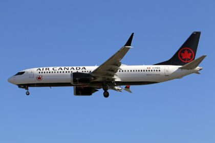 Air Canada Boeing 737-8 MAX flying, blue sky in background.