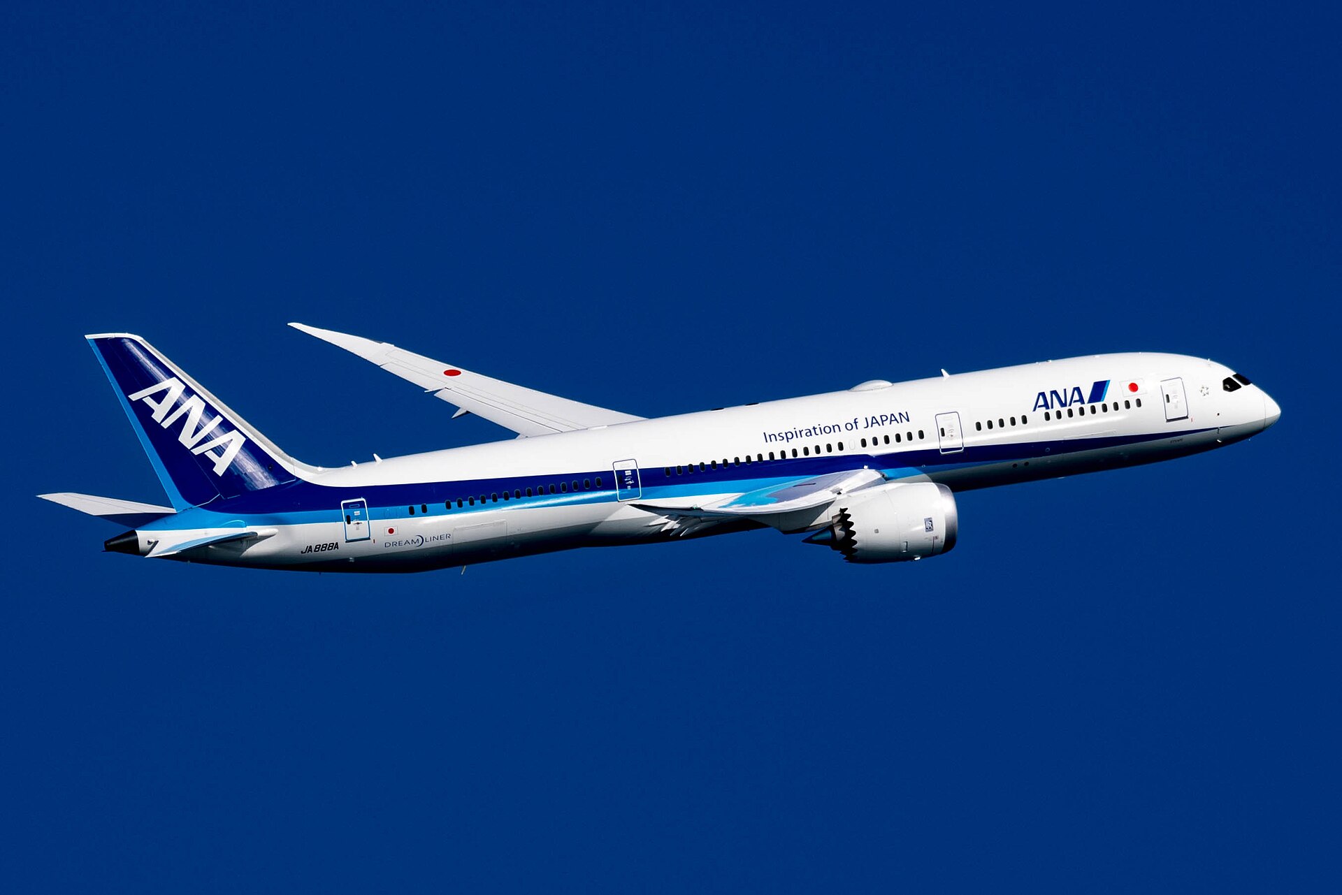 ANA Boeing 787 flying against clear blue skies.