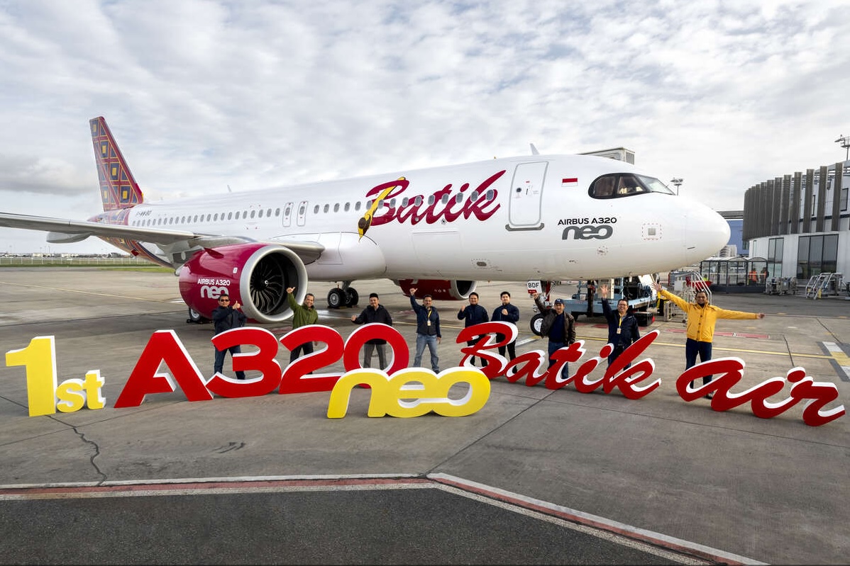 A group of people celebrating the delivery of a new Batik Air Airbus A320neo on a runway.