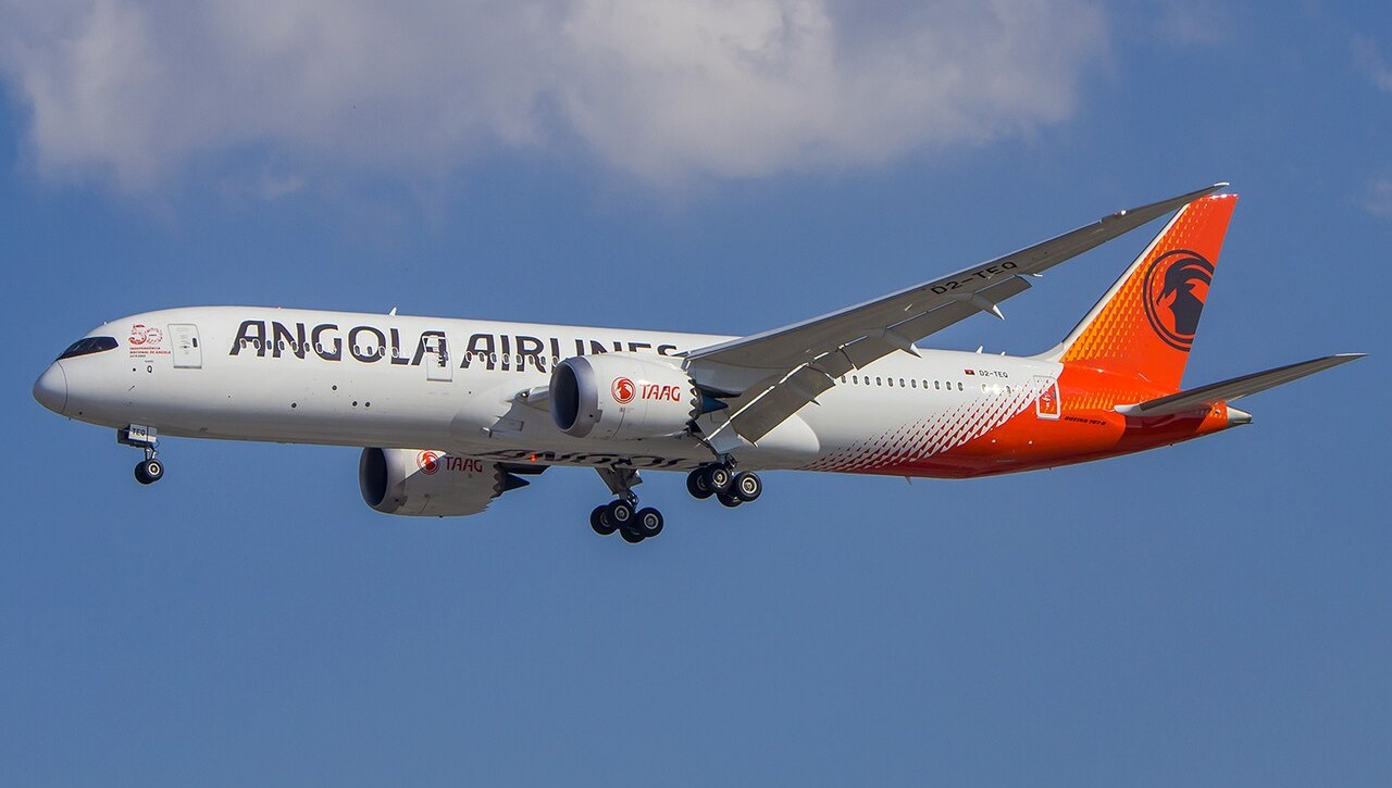 A TAAG Angola Airlines aircraft, flying in the blue sky.