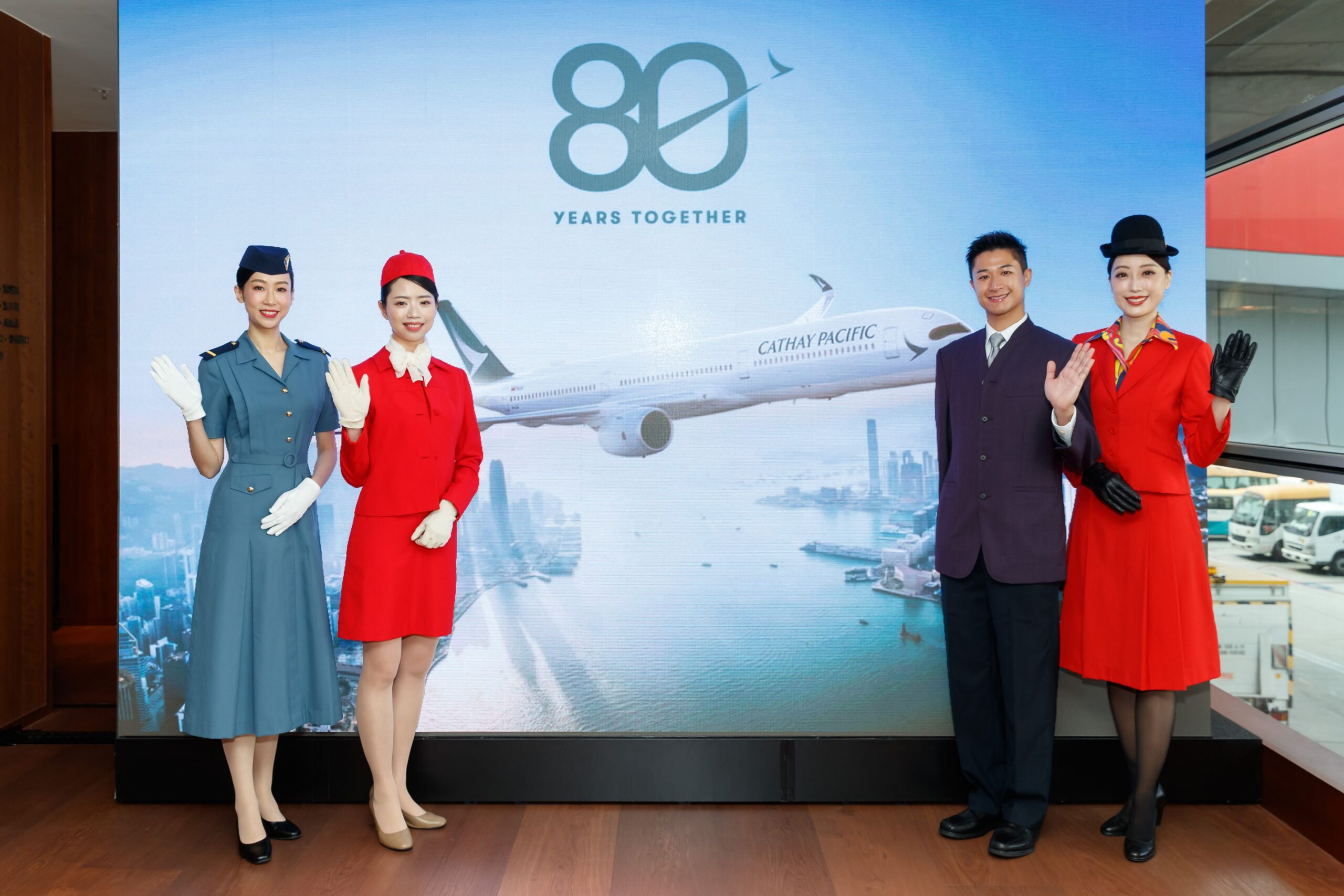Cabin crew of Cathay donned their vintage uniforms, in front of "80 years together" sign.