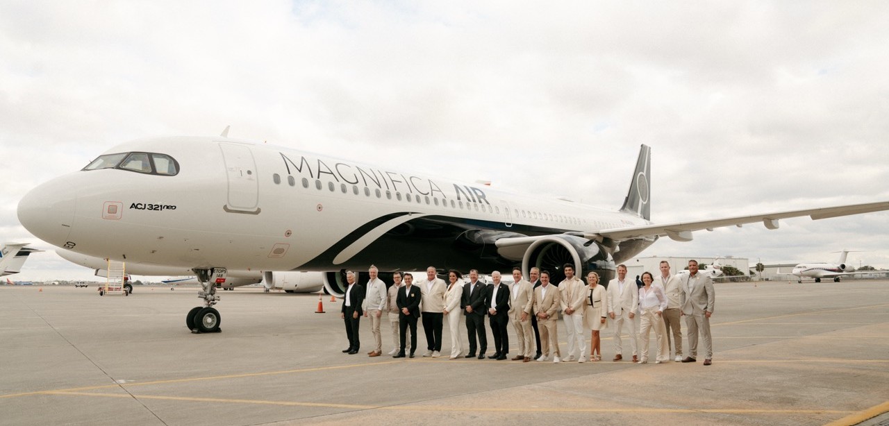 Magnifica Air aircraft on the tarmac with flight crew stood in front of it.