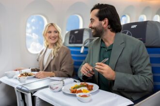 Passengers seated in LOT Polish Airlines Business Class enjoying a plated meal during a long-haul flight.