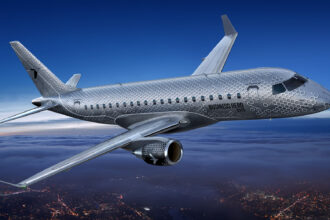 An E175 in flight, with the words "Business Hero" etched on the side of the aircraft.