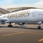 Emirates Boeing 777 on the tarmac, with the airline's name displayed in gold lettering along the fuselage