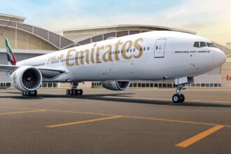 Emirates Boeing 777 on the tarmac, with the airline's name displayed in gold lettering along the fuselage