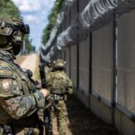 Three Polish Border Guard officers on patrol in a wooded area. The military is on high alert after repeated incidents of balloons smuggling cigarettes.