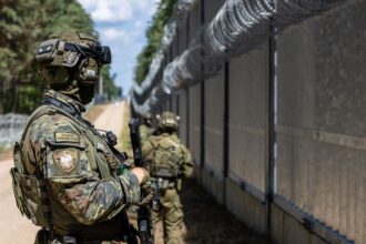 Three Polish Border Guard officers on patrol in a wooded area. The military is on high alert after repeated incidents of balloons smuggling cigarettes.