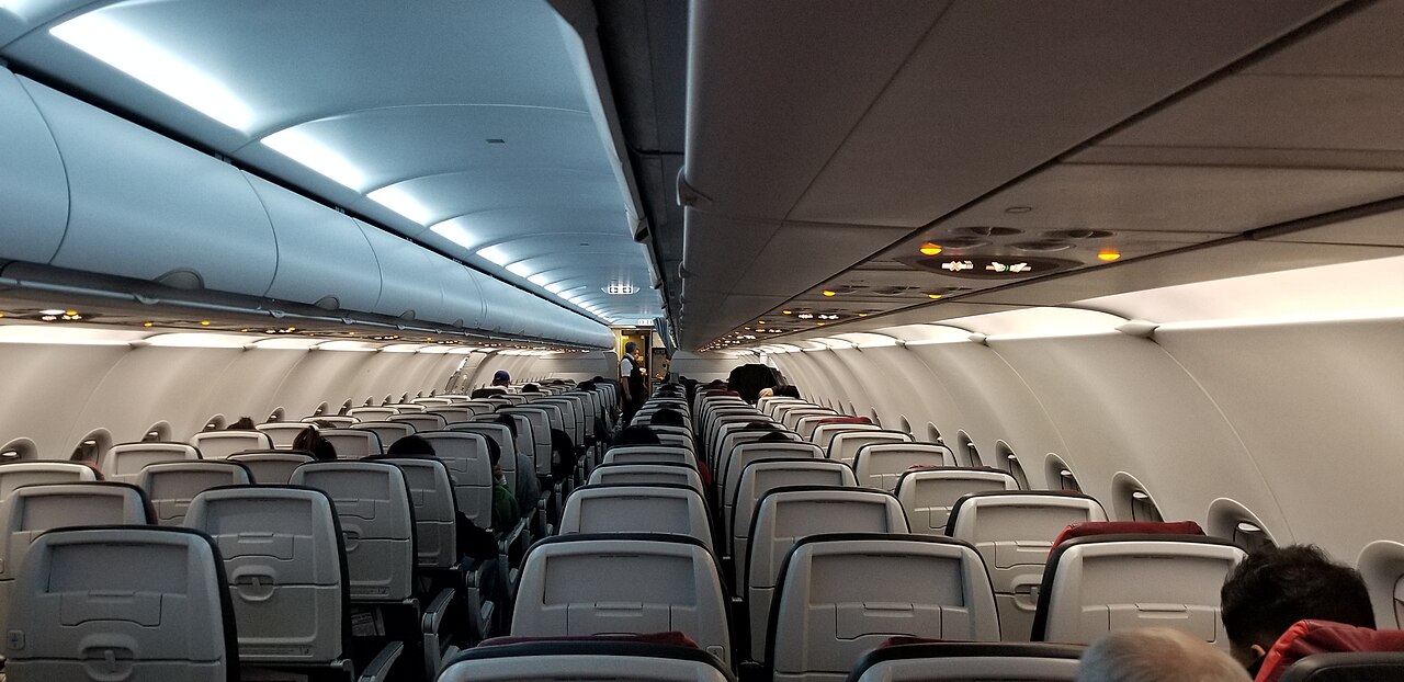 Interior of an Air Canada Rouge Airbus A321-200, plane seats and overhead lighting.
