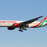 Kenya Airways Boeing 777-200ER flying against blue sky.