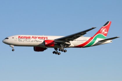 Kenya Airways Boeing 777-200ER flying against blue sky.