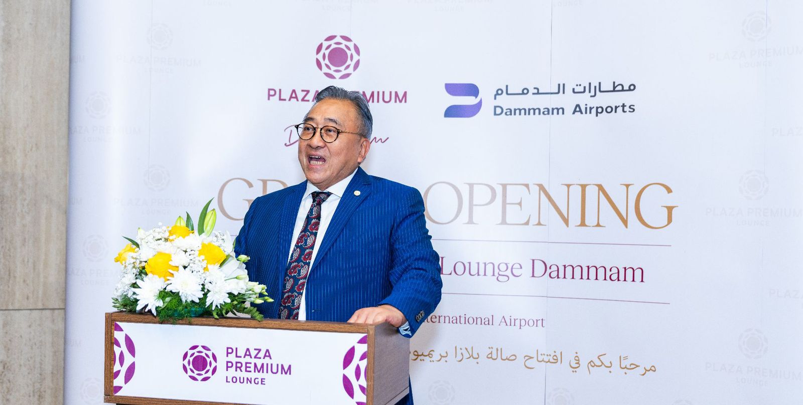 A man in glasses standing behind a podium during a ceremonial event.