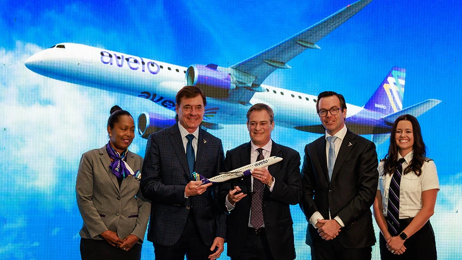 Five people stood in front of an Avelo aircraft picture, two people are holding an Embraer aircraft figurine. 