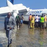 Aftermath of landing, depicting plane submerged in water on the beach.