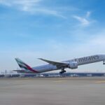 An Emirates Boeing 777-300ER aircraft in new livery taking off from Dubai International Airport runway.