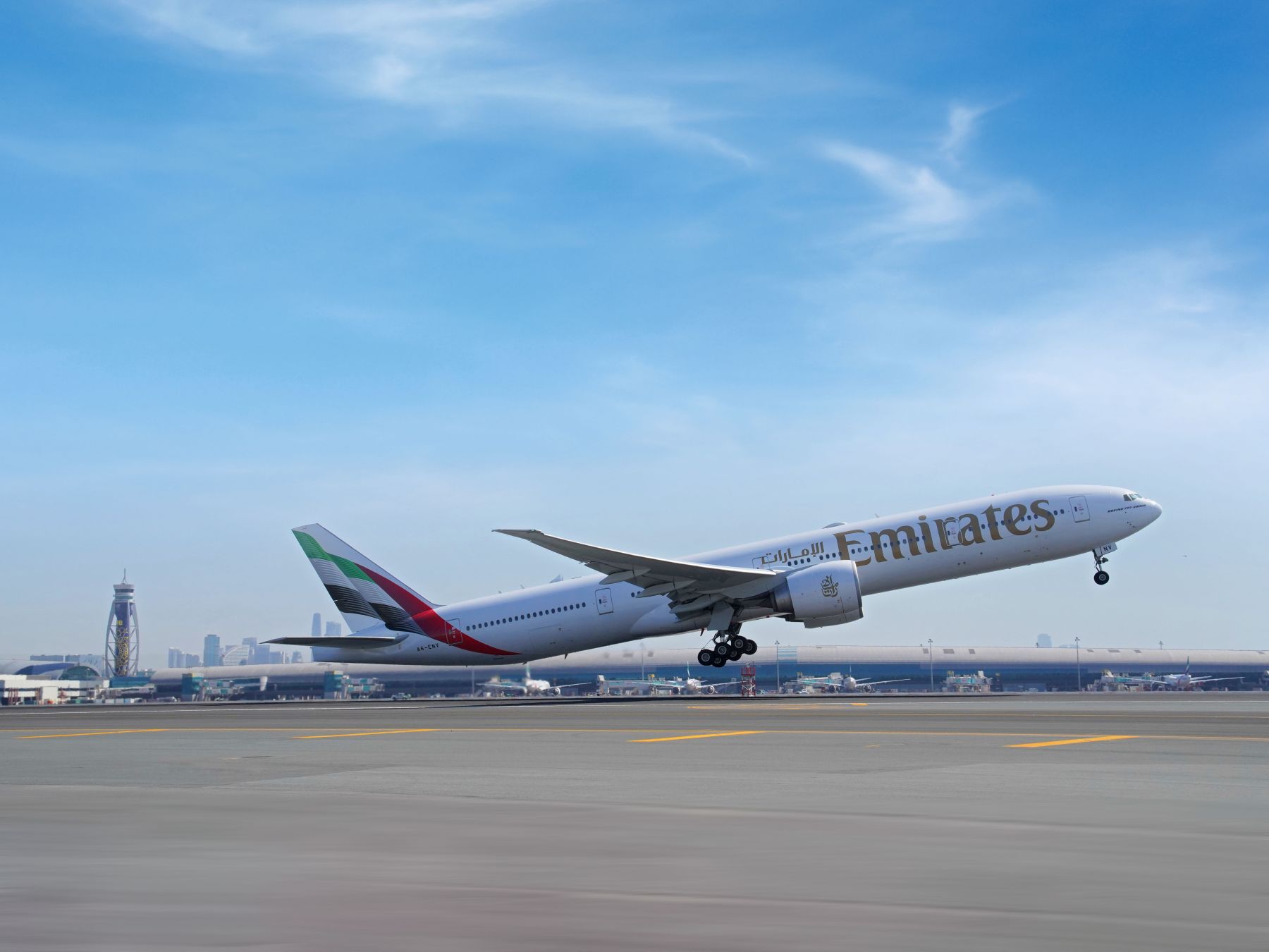 An Emirates Boeing 777-300ER aircraft in new livery taking off from Dubai International Airport runway.