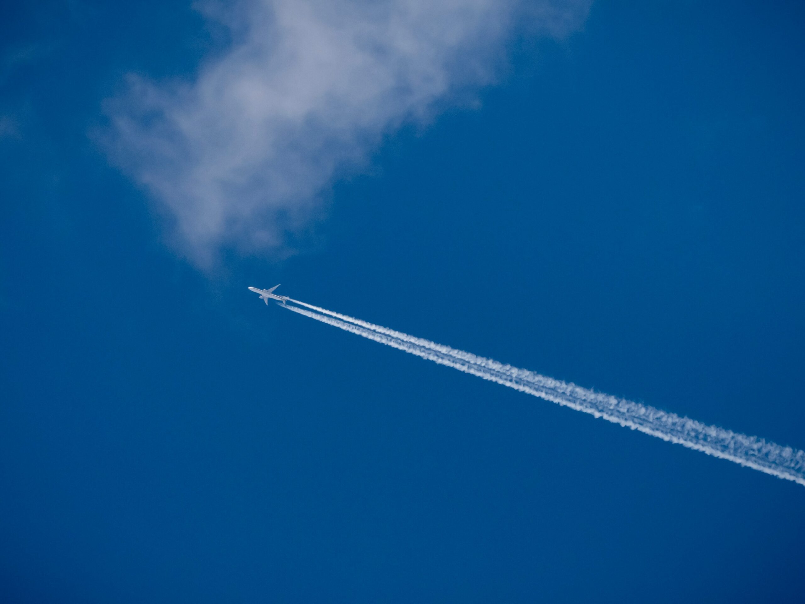 Image of airplane in the sky leaving a trail on contrail cloud.