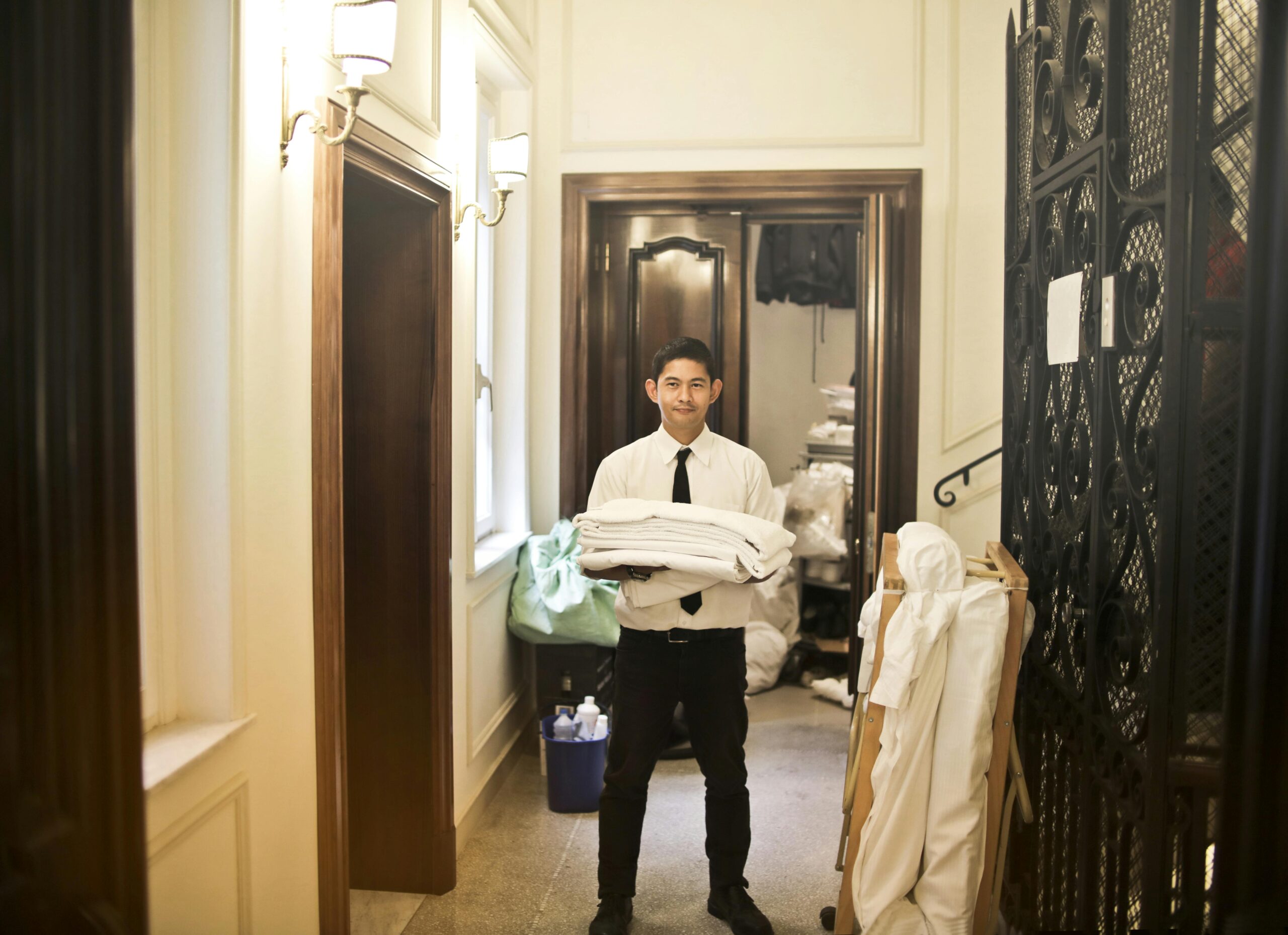 Hotel staff member dressed in elegant clothes holding the laundry in a corridor