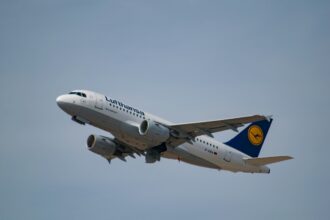 Lufthansa aircraft, flying in the grey sky.