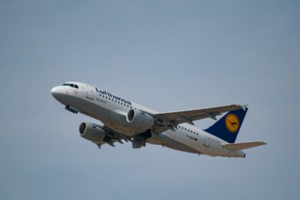 Lufthansa aircraft, flying in the grey sky.