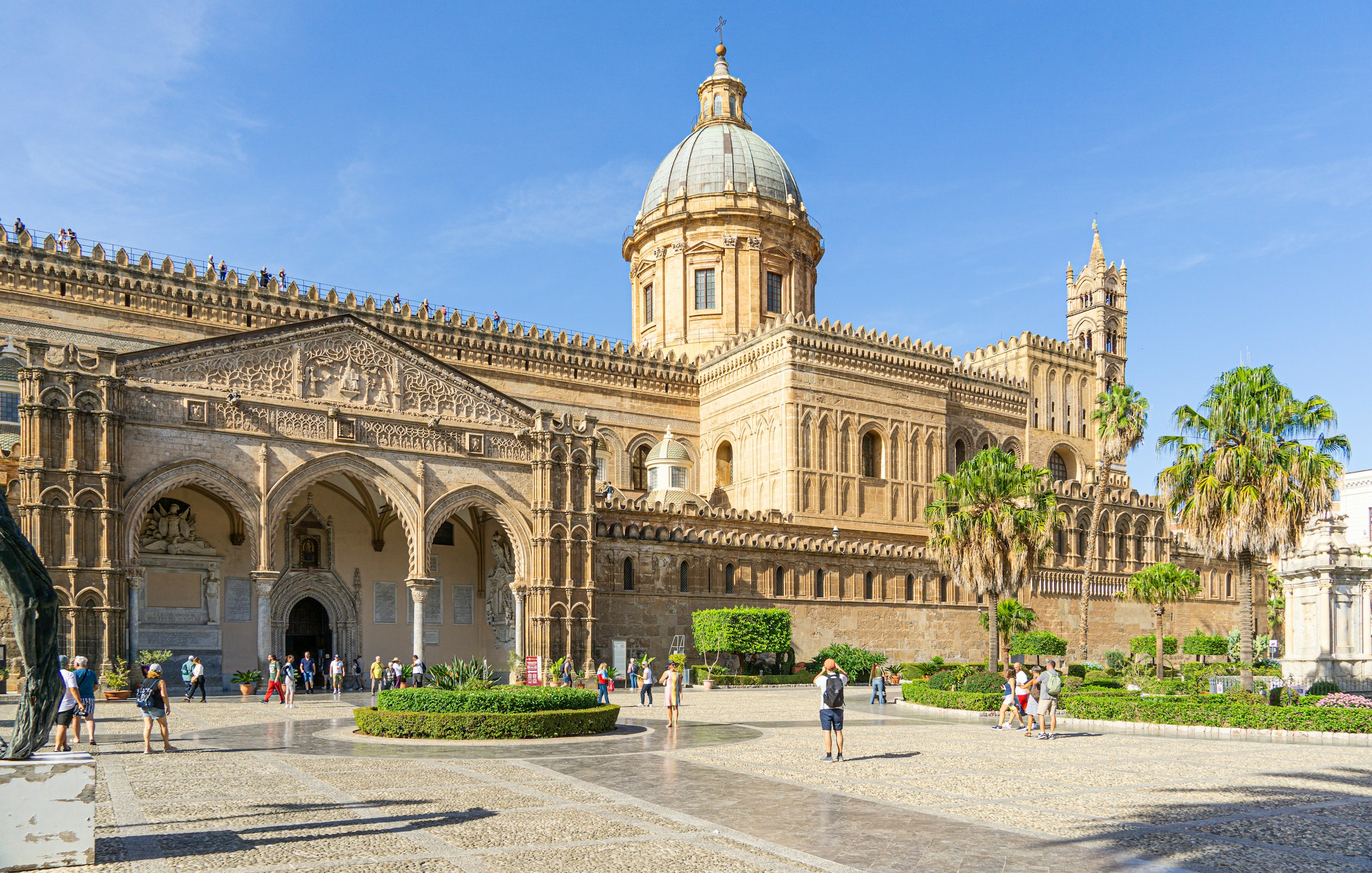 Building in Palermo, Sicily, tourists outside, blue sky in the background.